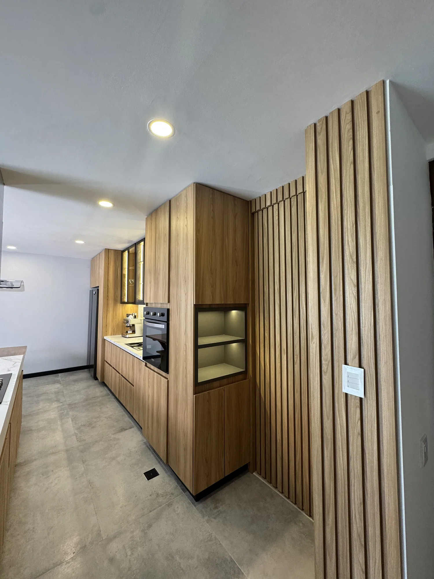 Mobiliario integral en madera con torre de hornos y panel decorativo