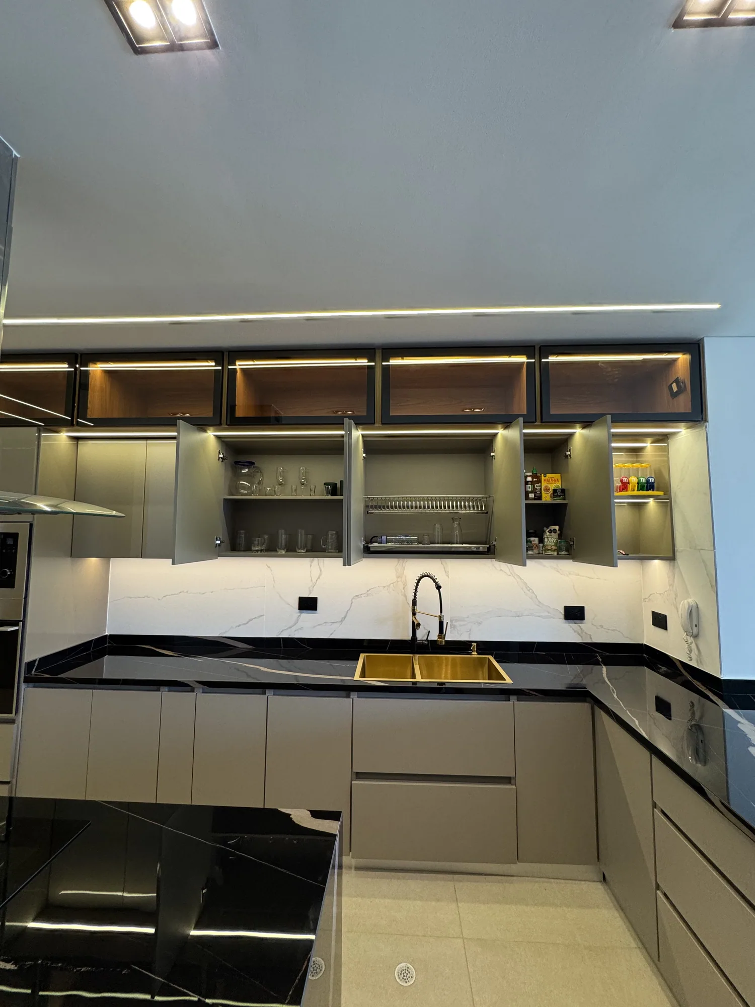 Cocina en L con gabinetes superiores iluminados y meson claro